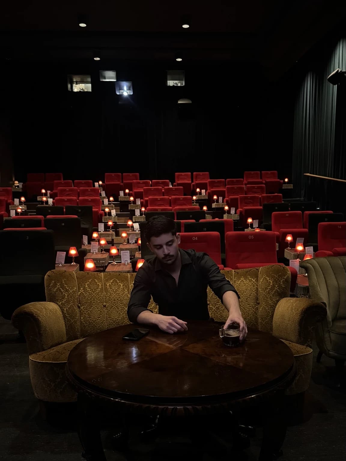Hugo Hompe seated at a wooden table in the original cinema lounge, with red seats and warm table lamps